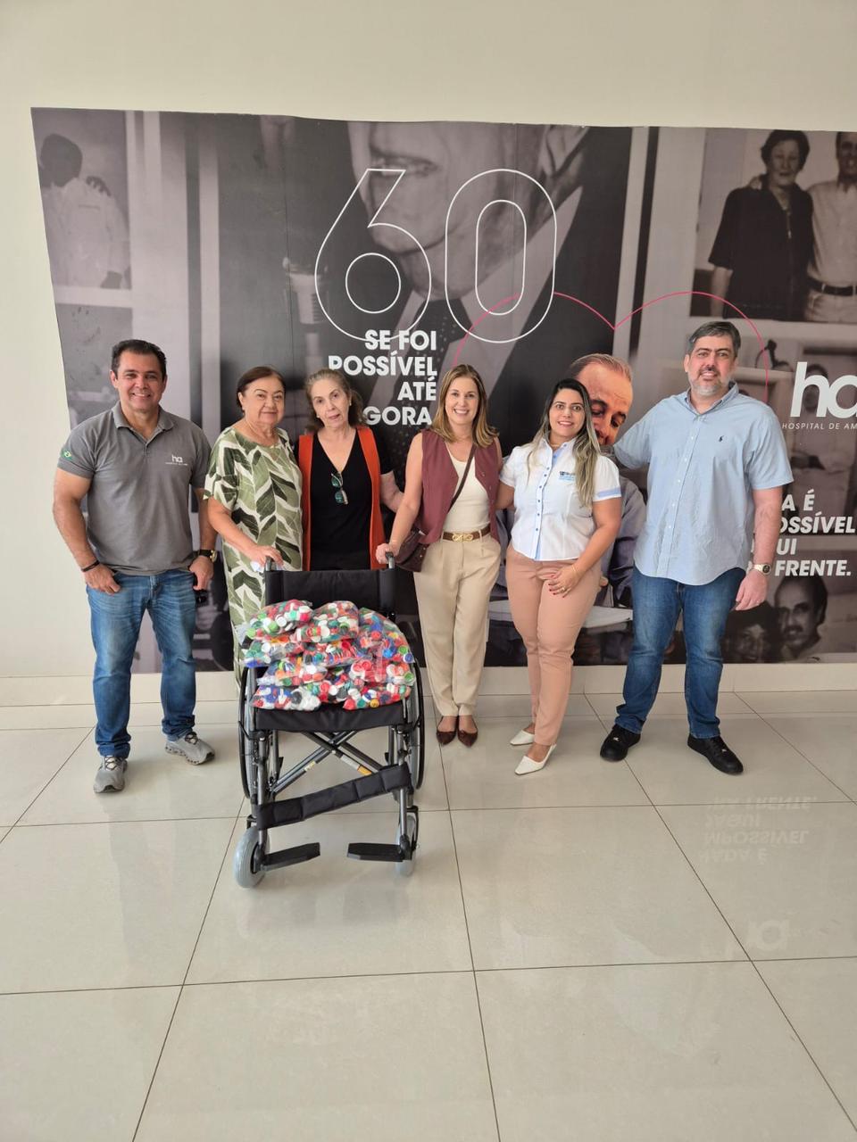 Delegação de Colmeia-TO reunida ao lado da cadeira de rodas com tampinhas no Hospital de Amor
